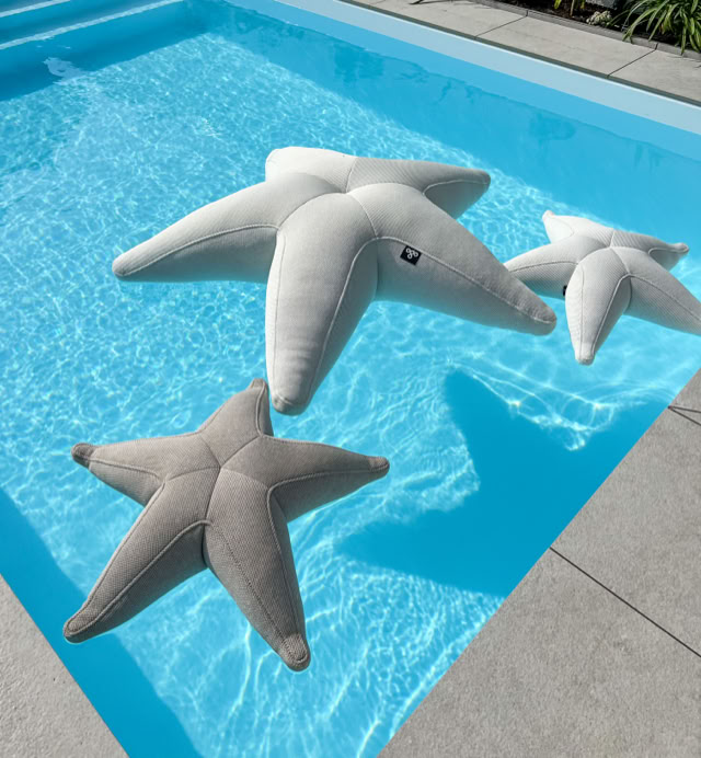Drei sternförmige Kissen schwimmen in einem blauen Pool.